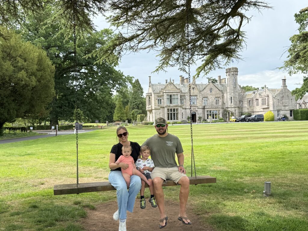 family in front of schloss roxburghe, a castle hotel in southern scotland, booked on a trip to england & scotland on points & miles
