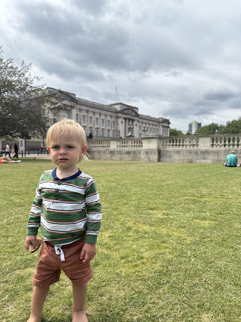 toddler in front of buckingham palace during a picnic on a london family trip. 