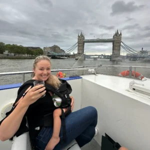 Mom holding sleeping toddler on river cruise next to Tower Bridge