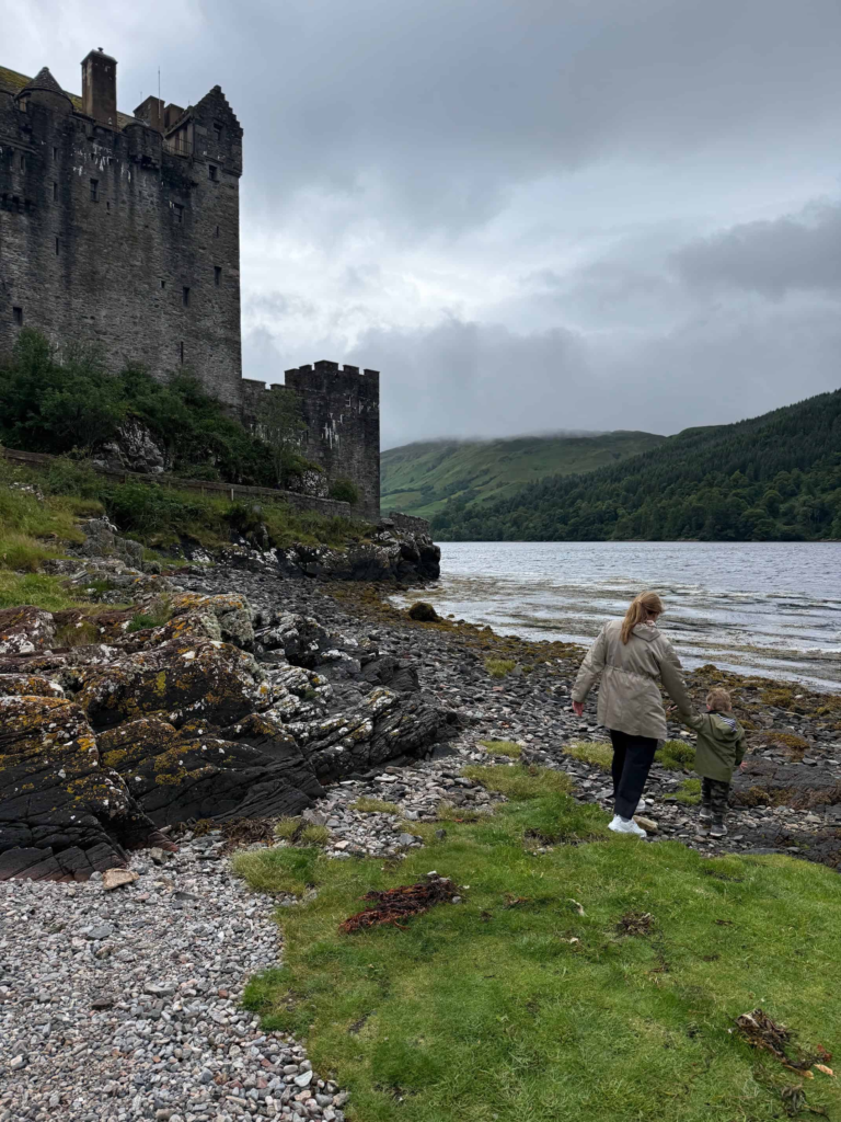 A woman and toddler exploring the shores outside Eilean Donan Castle