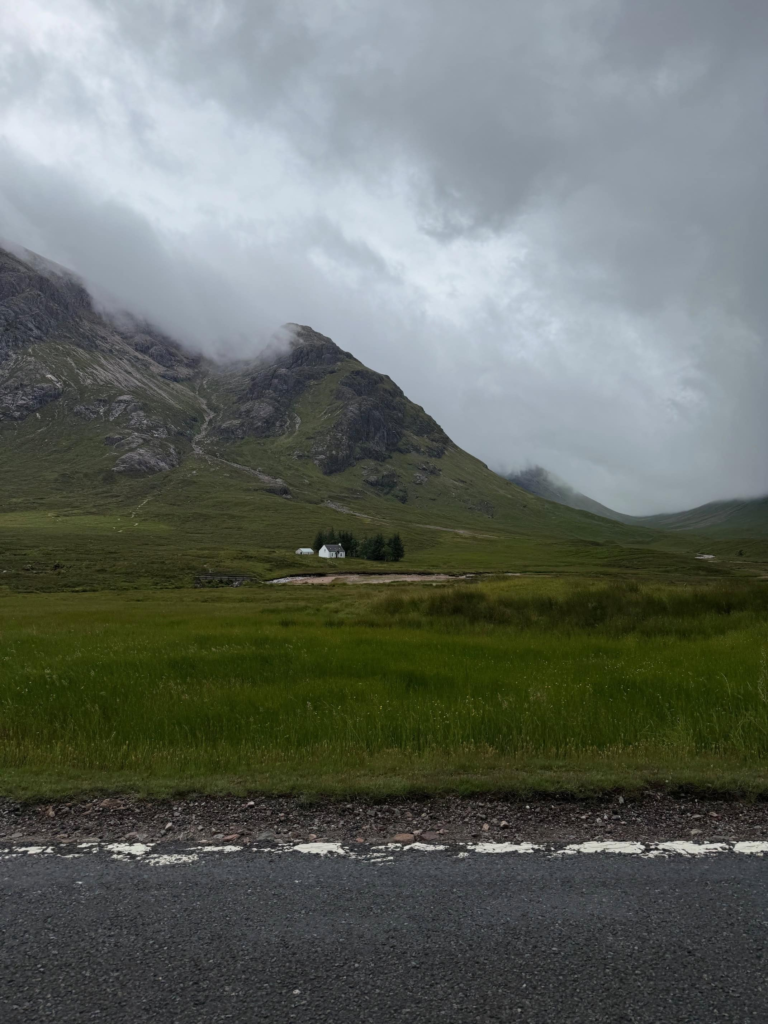 A beautiful view in Glencoe Scotland of mountains and a small white house in a valley