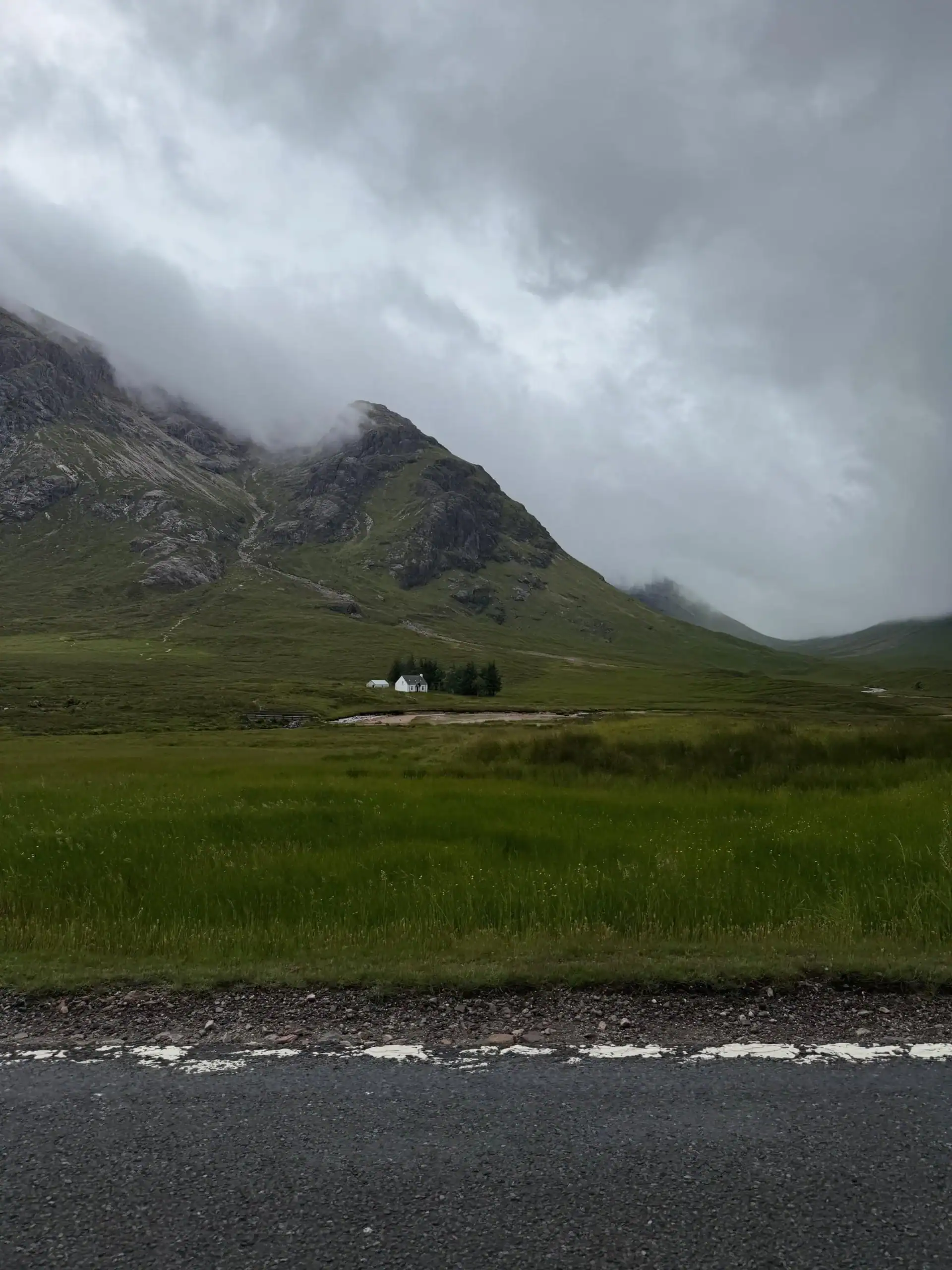 A beautiful view in Glencoe Scotland of mountains and a small white house in a valley