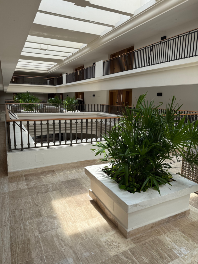 Looking into the open air hallway at Marriott Cancun All Inclusive Resort. Views of seating area and palm trees