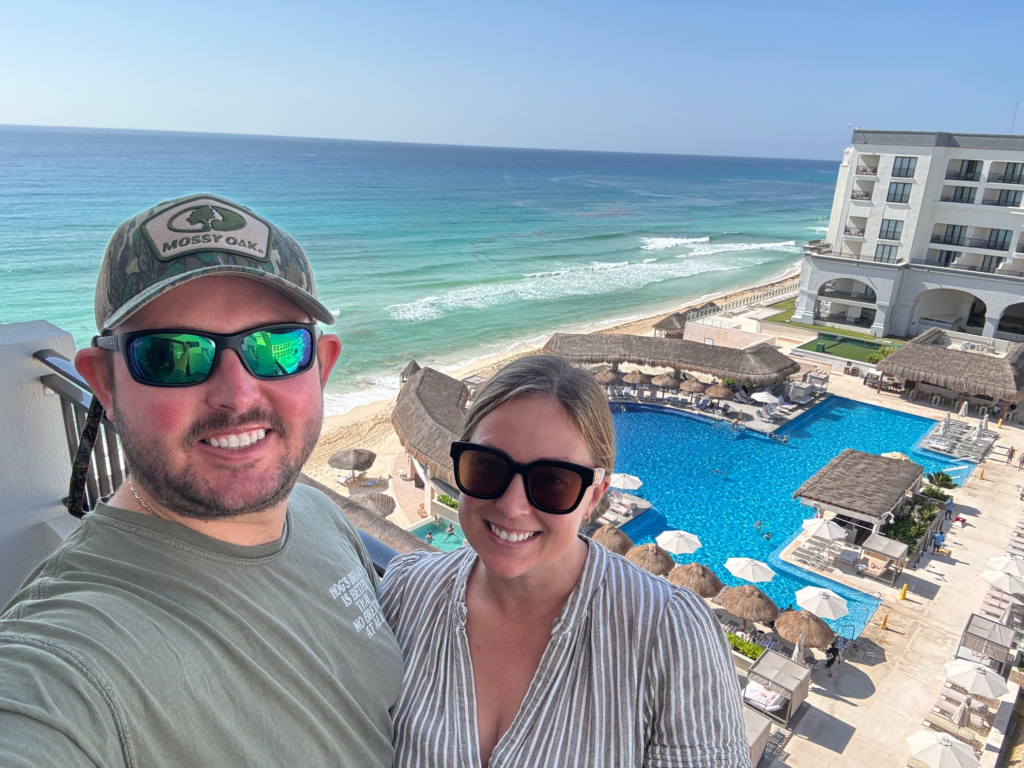 Couple on hotel balcony overlooking the pool and ocean at Marriott Cancun All Inclusive