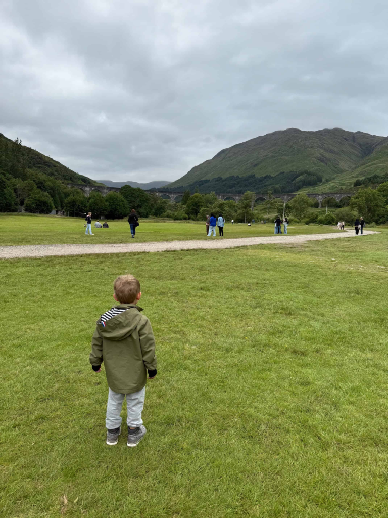 toddler watches jacobite steam train from the glenfinnan viaduct