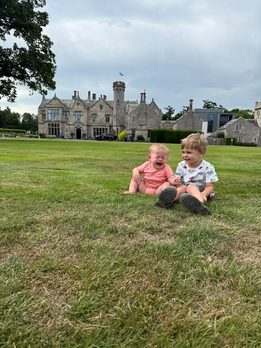 Baby crying and toddler sitting in front of Schloss Roxburghe Castle